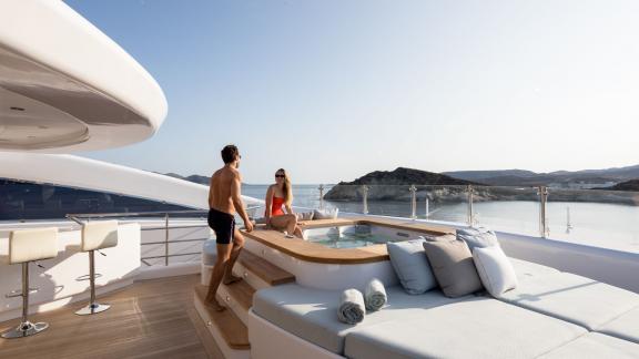 Luxurious hot tub on the Opari yacht, surrounded by comfortable loungers and views of the sea and coastline.